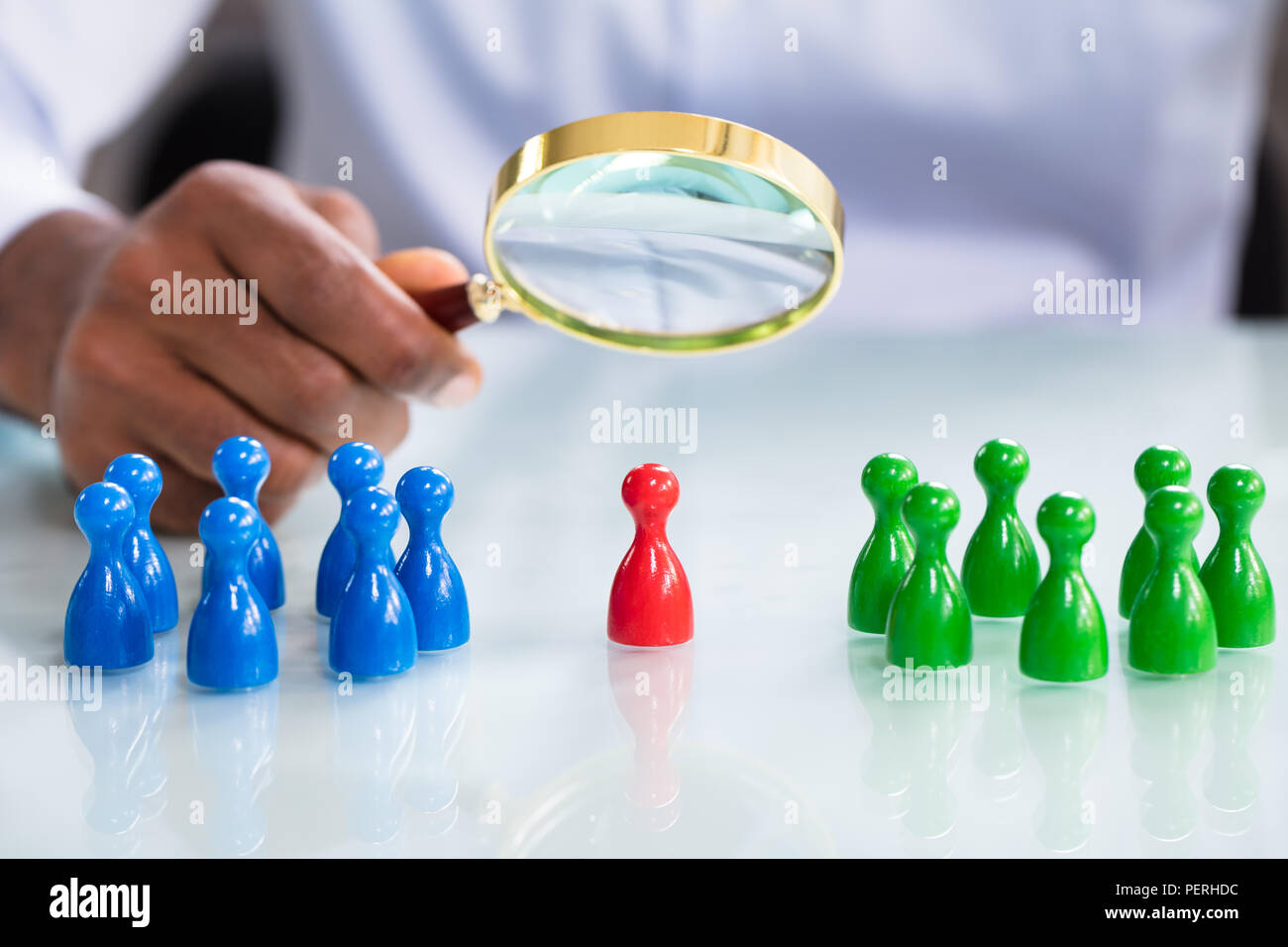 Un homme à la couleur de pions avec loupe sur le bureau Banque D'Images