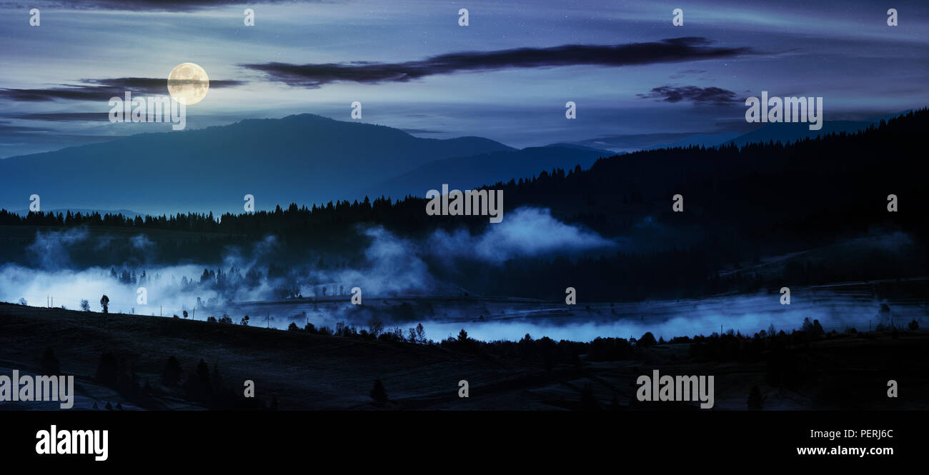 Panorama de campagne dans la nuit dans la lumière de la pleine lune. beau paysage dans les montagnes avec le brouillard se lever au-dessus de la vallée et colline Banque D'Images