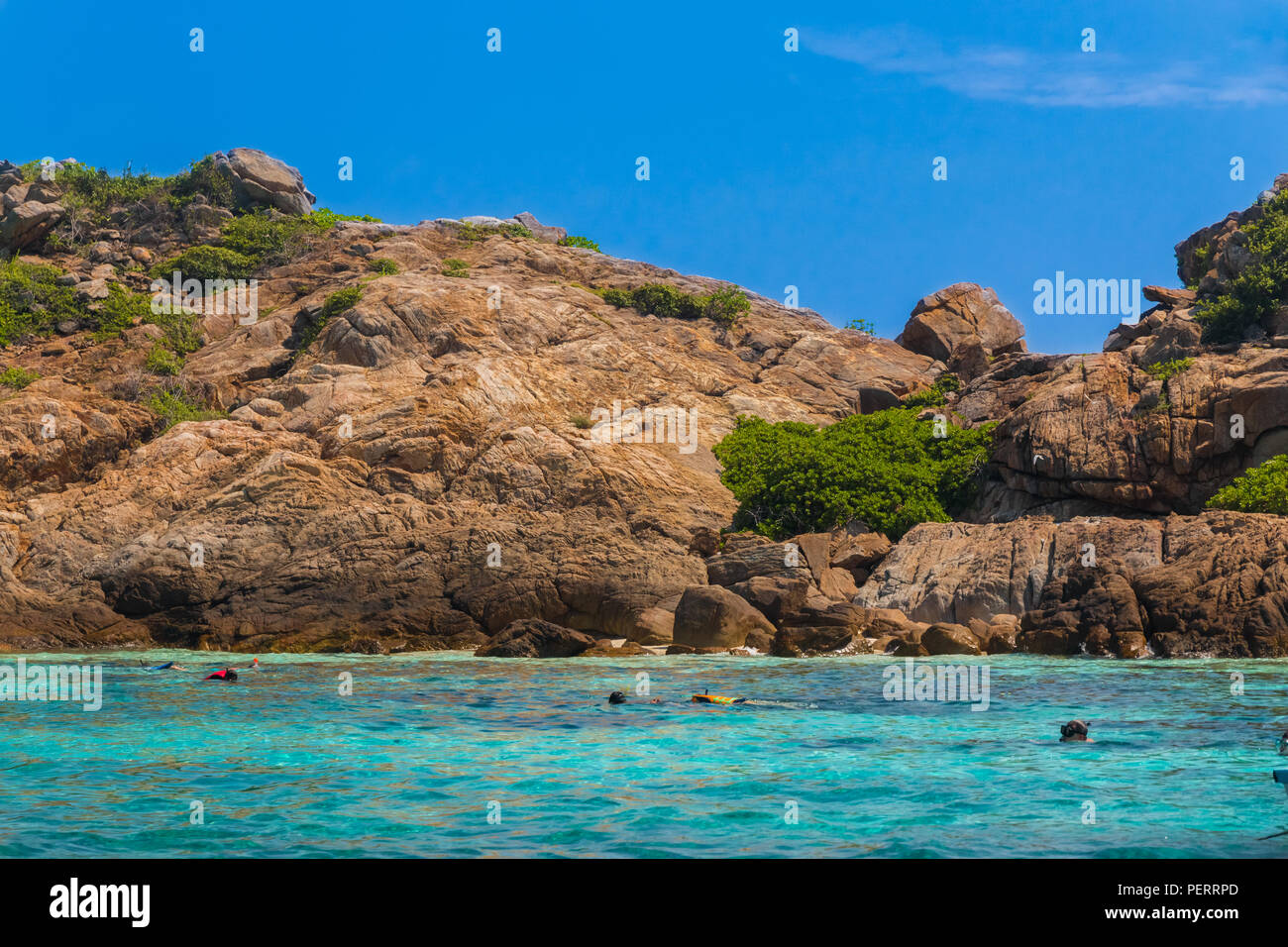 Beau paysage avec un ciel bleu, l'eau turquoise et les touristes de la plongée avec tuba en face de l'imposant rocher rochers de Tokong Burung (île aux oiseaux), un populaire... Banque D'Images