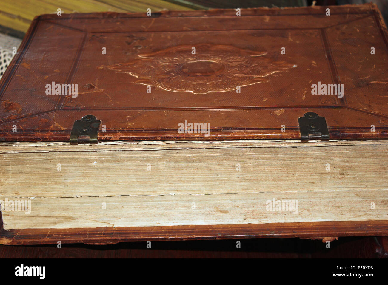 Vieux livre relié de cuir marron fermé avec les captures de cuivre et l'empreinte en relief sur le couvercle signe couché sur le côté Banque D'Images