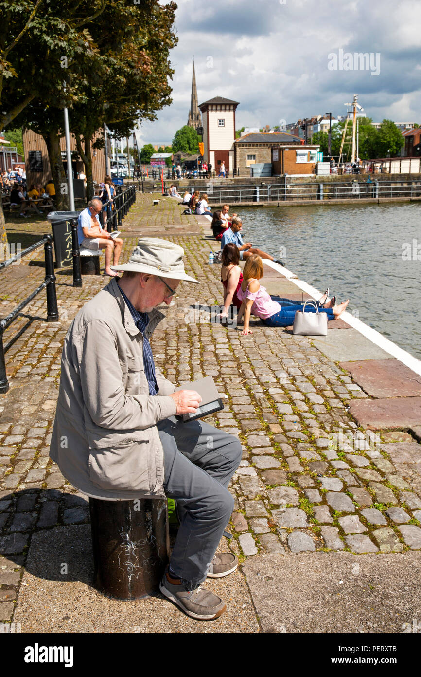 Royaume-uni, Angleterre, Bristol, port, Man reading kindle e-reader sur le quai à l'extérieur de la galerie Arnolfini Banque D'Images
