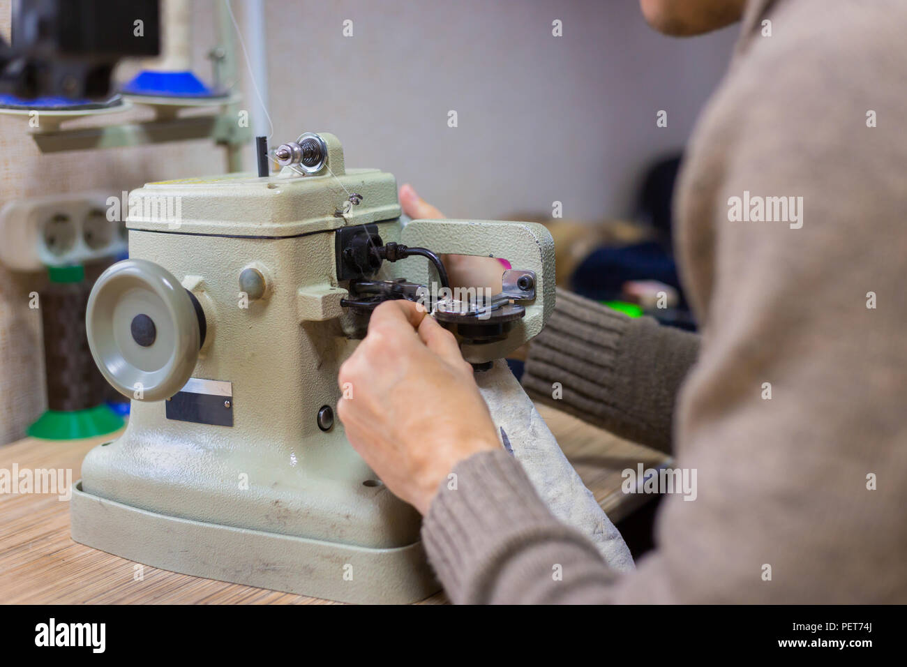 Professionnel hommes skinner, fourreur à l'aide de la machine à coudre spéciale pour coudre la peau de fourrure à l'atelier, atelier. La mode et le travail du cuir concept Banque D'Images