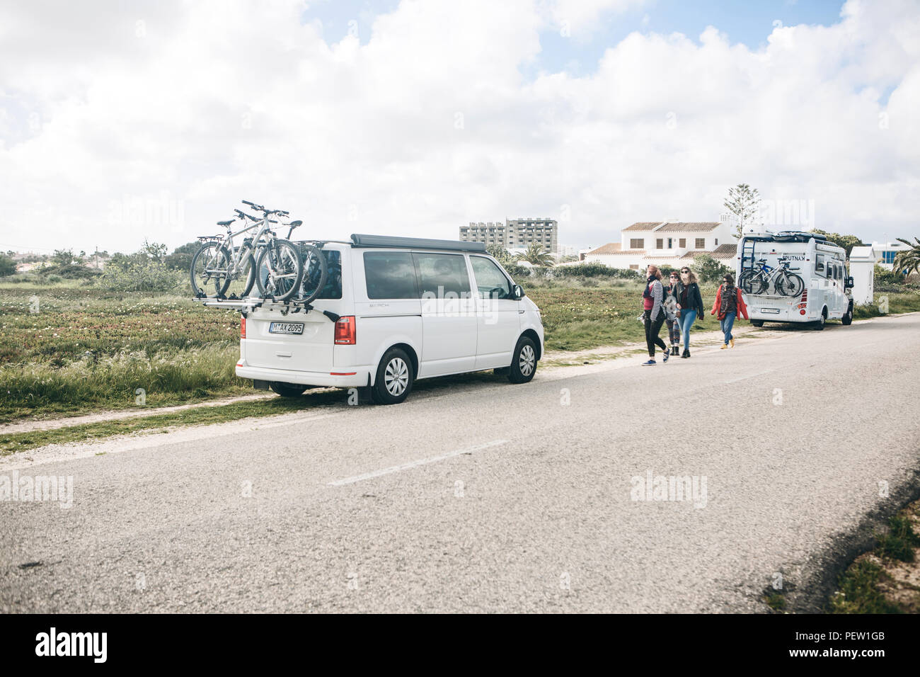 Le Portugal, Lagos, 12 avril 2018 : Voitures pour voyager avec des vélos garés sur le côté de la route. Les personnes à proximité à pied. Le repos actif et des voyages en famille. Banque D'Images