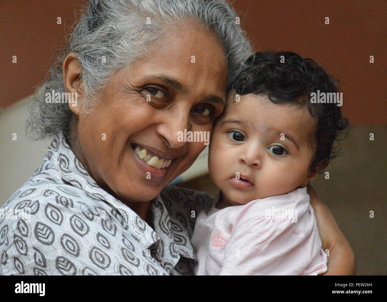 Près d'une grand-mère avec un grand sourire, étroitement et avec amour holding sa douce petite princesse Banque D'Images