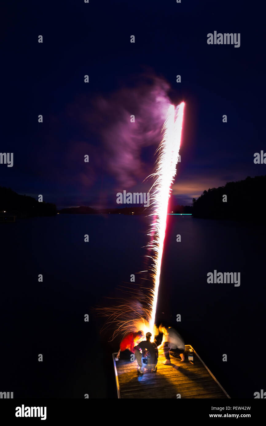 Un groupe d'amis d'artifice éclairage éteint sur un quai au bord du lac la nuit. Banque D'Images