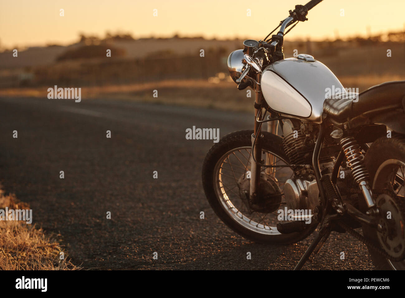 Moto Vintage garée sur empty country road. Moto Vintage debout au bord de la route en soirée. Banque D'Images