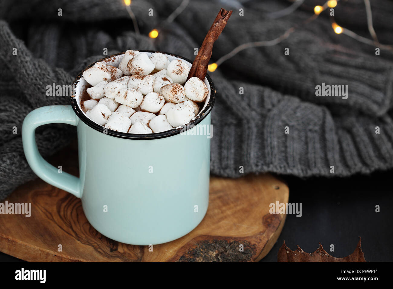 L'émail bleu et noir tasse de chocolat chaud avec des guimauves et écorce de cannelle. L'extrême profondeur de champ avec l'accent sur la consommation. Banque D'Images