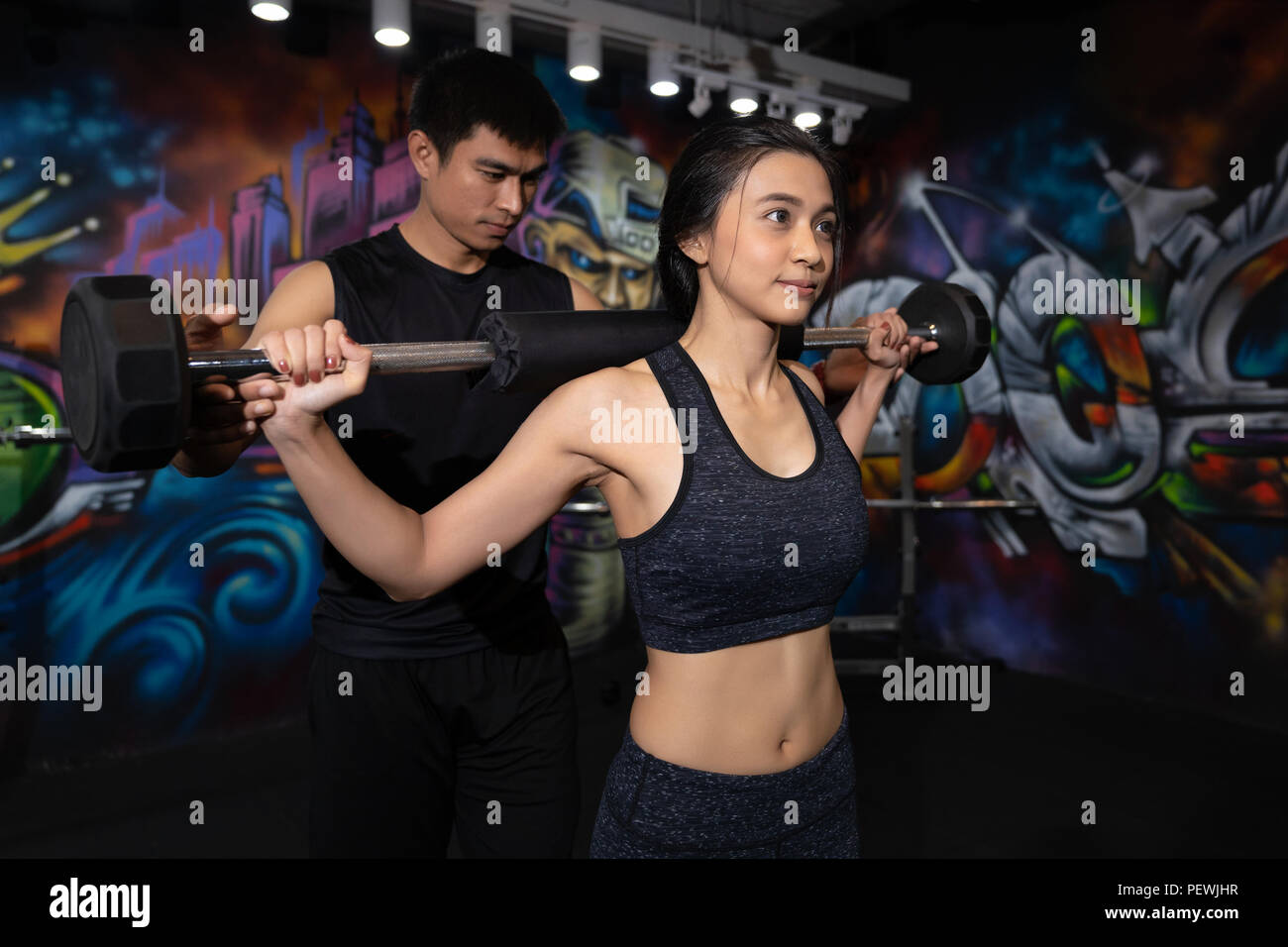 Poids de levage femme Fitness, musculation, Sport, mode de vie et de personnes concept - Young man and woman flexing muscles de l'épaule et de faire Banque D'Images