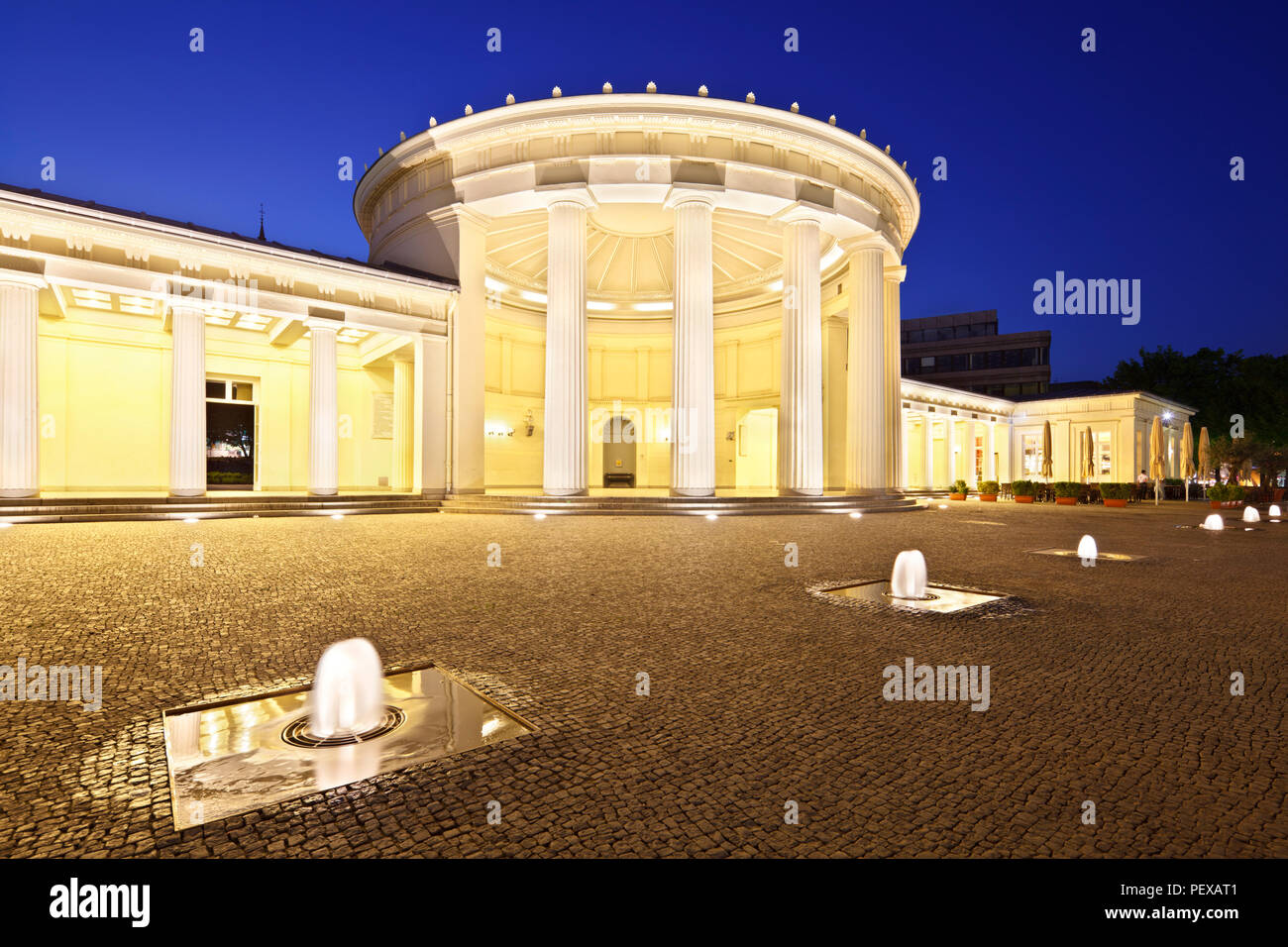L'Elisenbrunnen célèbre à Aix-la-Chapelle, Allemagne. Nuit illuminée de ciel bleu et quelques fontaines dans l'avant-plan. Banque D'Images