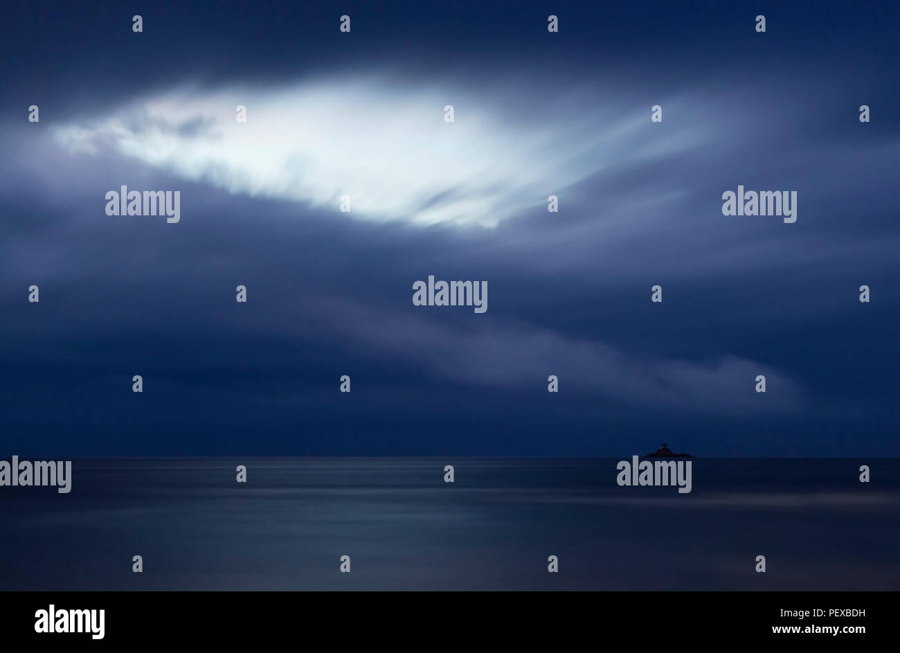 Île Saint-Pierre sous des nuages sombres avec le dernier soir lumière brillant à travers un trou dans les nuages. La Digue, Seychelles. Banque D'Images