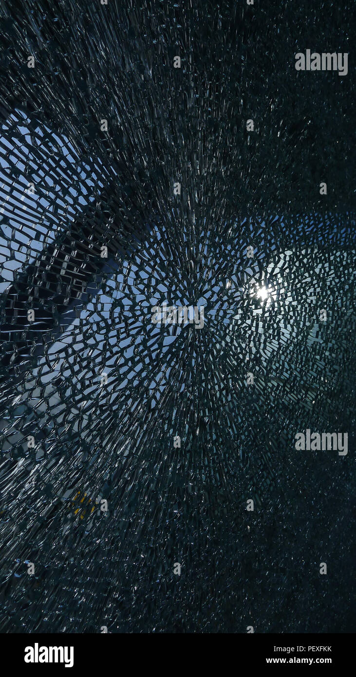 Des fissures dans la surface du verre avec un petit trou au milieu Banque D'Images