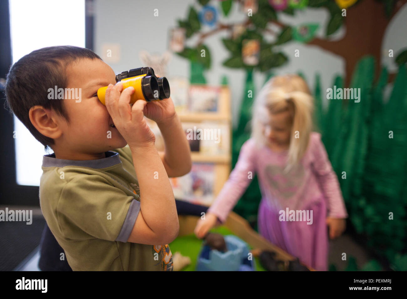 À l'aide de jumelles jouet garçon in classroom Banque D'Images