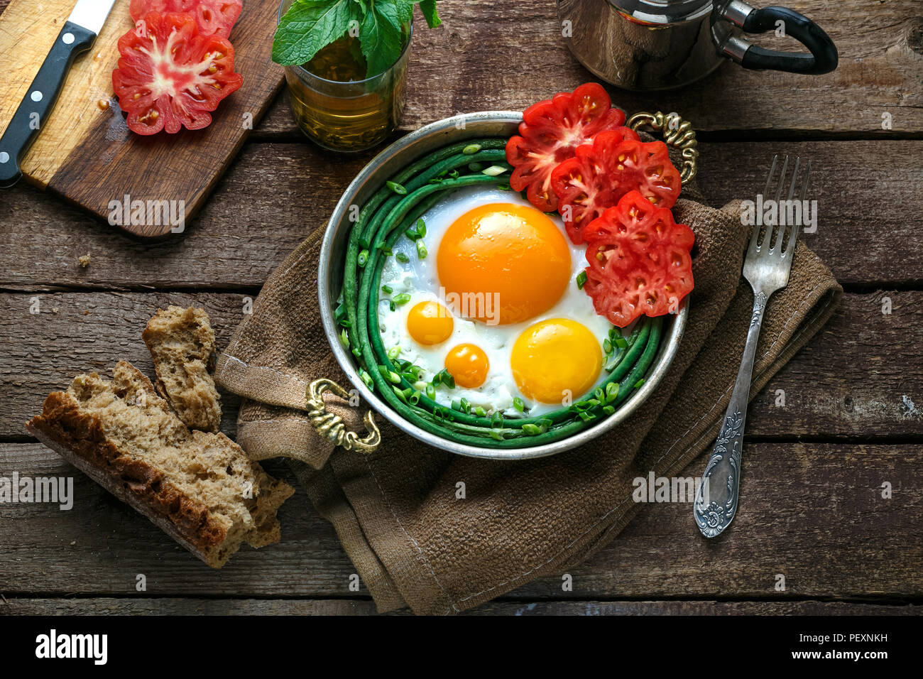 Côté ensoleillé d'œufs au plat dans une casserole en cuivre avec les tomates et les haricots verts, l'espace de copie. Banque D'Images