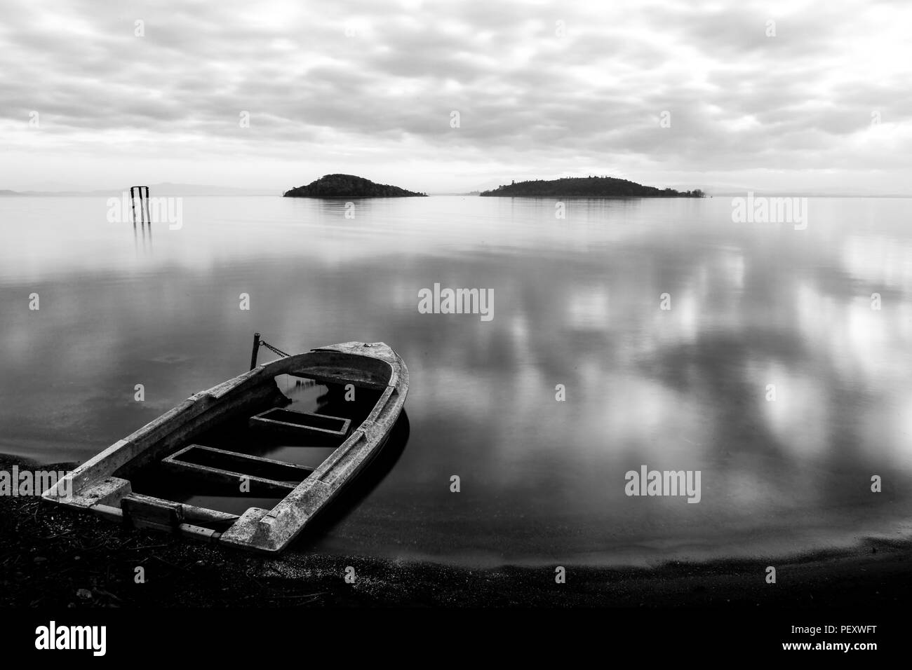 Belle vue sur le lac Trasimeno (Ombrie) au crépuscule, avec un peu de vieux bateau, par l'eau, partiellement rempli d'eau et d'un toujours parfaitement maquereaux ciel Banque D'Images
