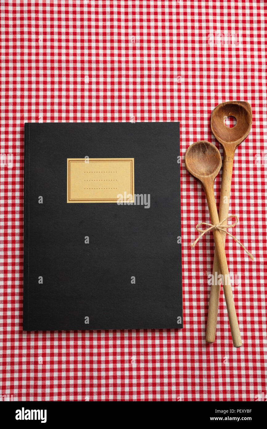 Livre de recettes de cuisine. Ordinateur portable et d''ustensiles de cuisine en bois sur l'nappe rouge, vue du dessus Banque D'Images