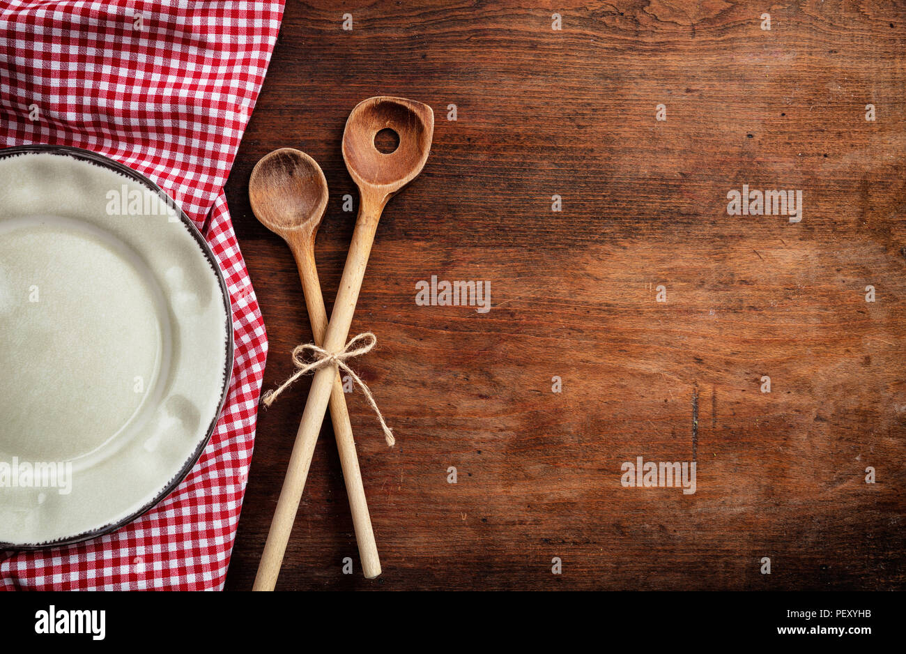 Lieu rustique. La plaque vide, des ustensiles de cuisine et nappe rouge sur la table en bois, vue du dessus, copy space Banque D'Images