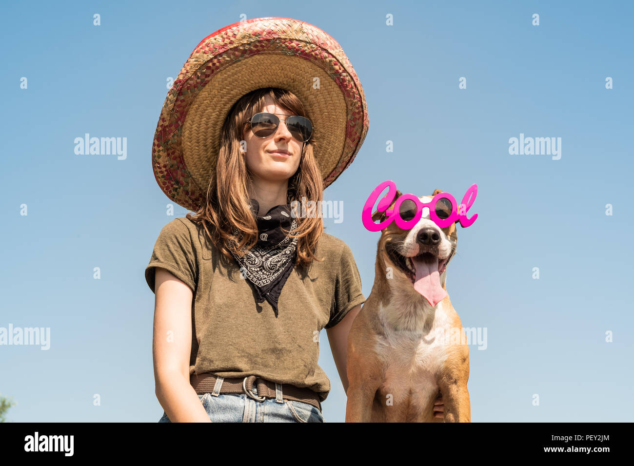 Belle fille de Mexican Hat déguisé en bandit de gangster avec chien dans cool lunettes de soleil. Personne de sexe féminin en chapeau sombrero et bandana posant avec pupp Banque D'Images
