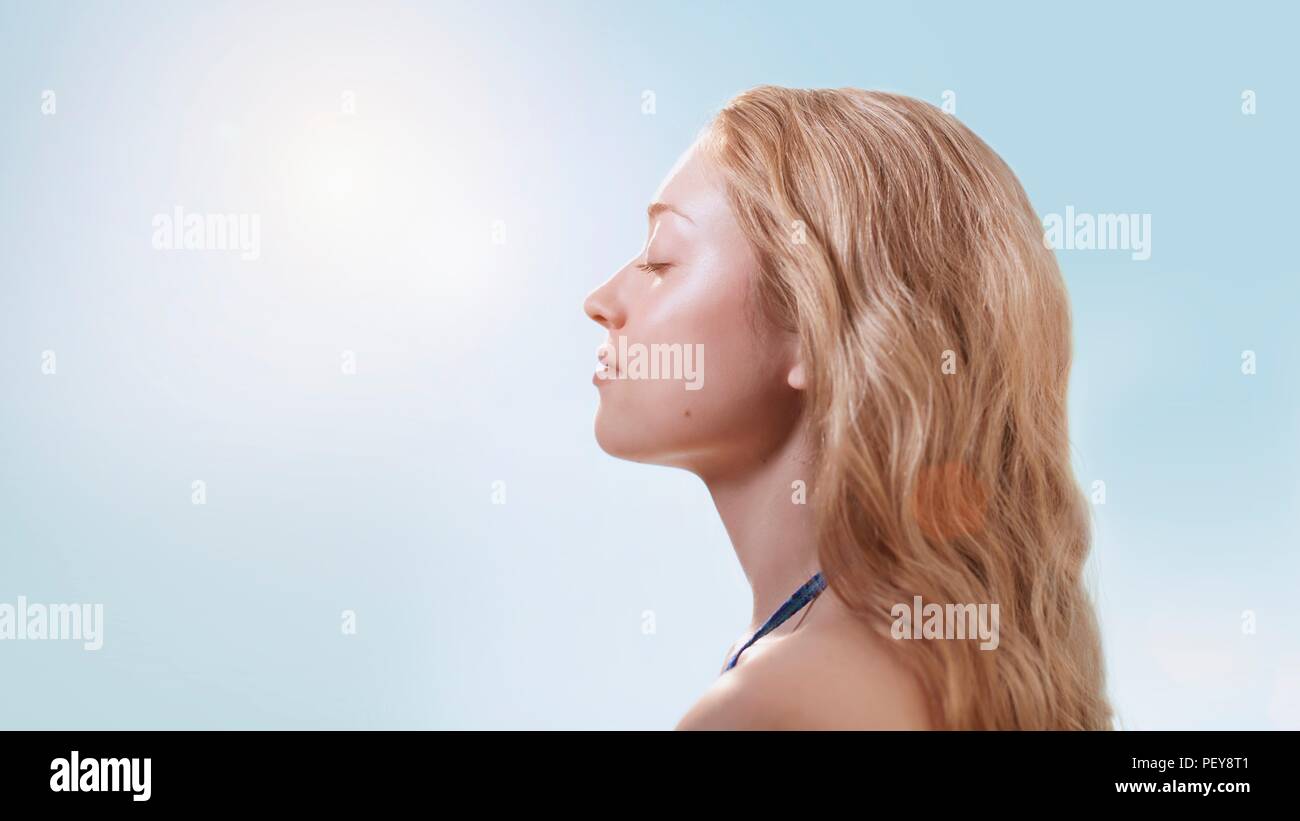 Femme dans la lumière du soleil avec les yeux fermés. Banque D'Images