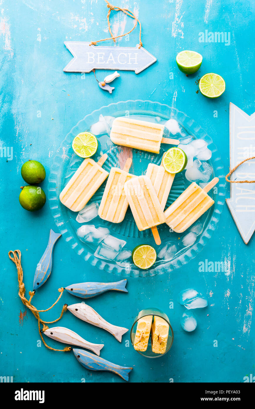 Sucettes de mangue sur une plaque de verre avec de la glace pilée, autour du poisson en bois artisanal et une pancarte en bois avec le texte bech, summertime concept. Banque D'Images