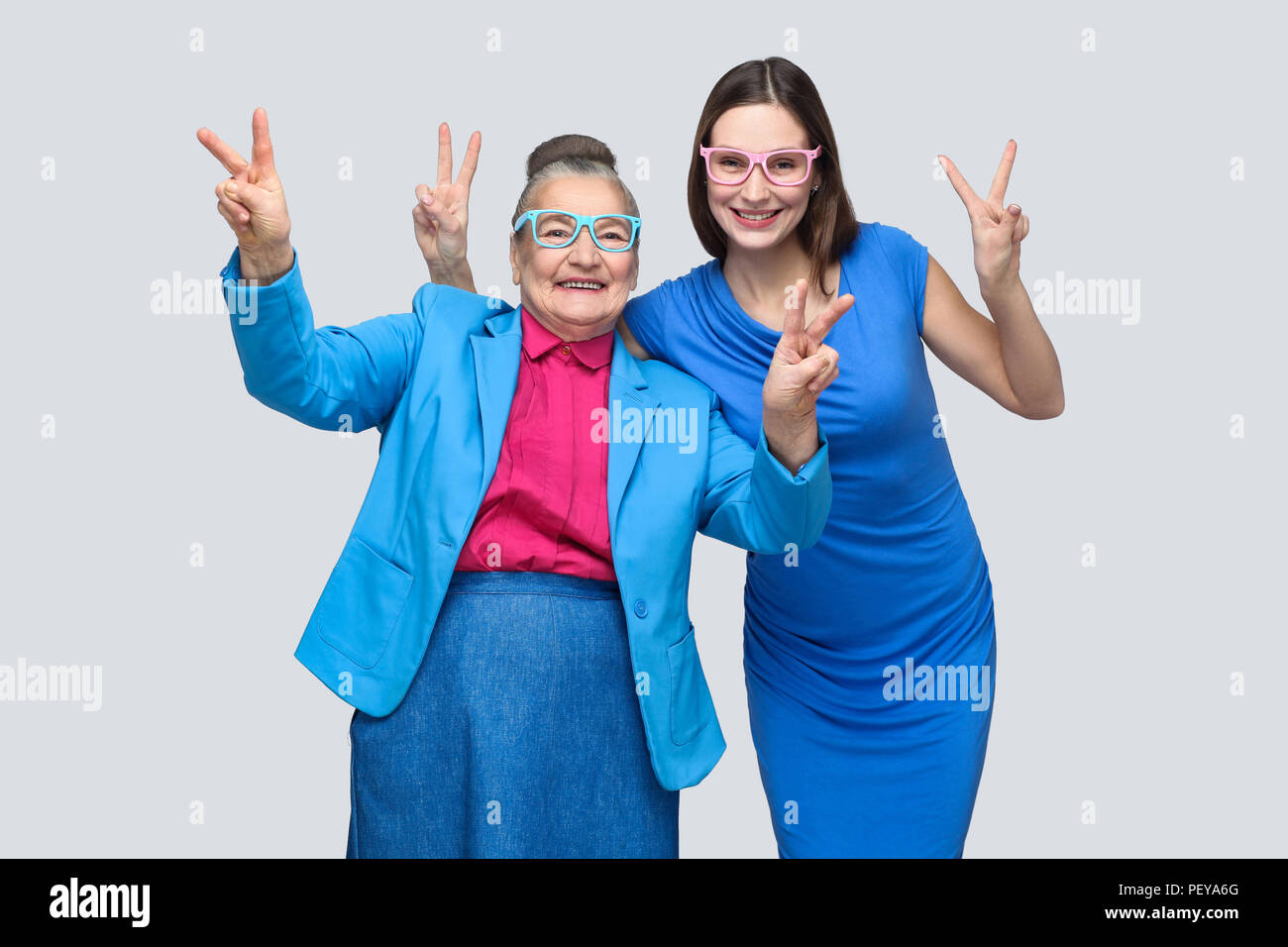 Grand-mère avec sa petite-fille montrant la paix ou la victoire, looking at camera avec sourire à pleines dents. Les relations dans la famille. Le bonheur et la famille relation Banque D'Images