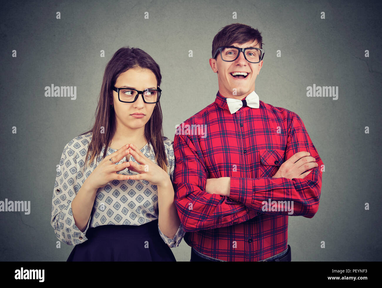 Jeune couple de personnages différents avec gai homme heureux et grincheuse femme négatif sur fond gris Banque D'Images