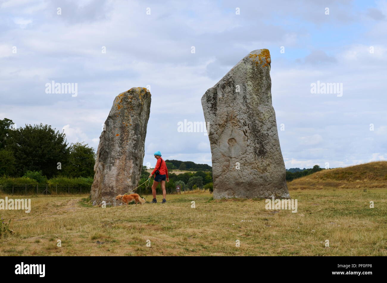 Une femme promener son chien à Avebury, un monument contenant trois cercles de pierres, autour du village d'Avebury dans le Wiltshire, dans le sud-ouest de l'Angleterre. Banque D'Images