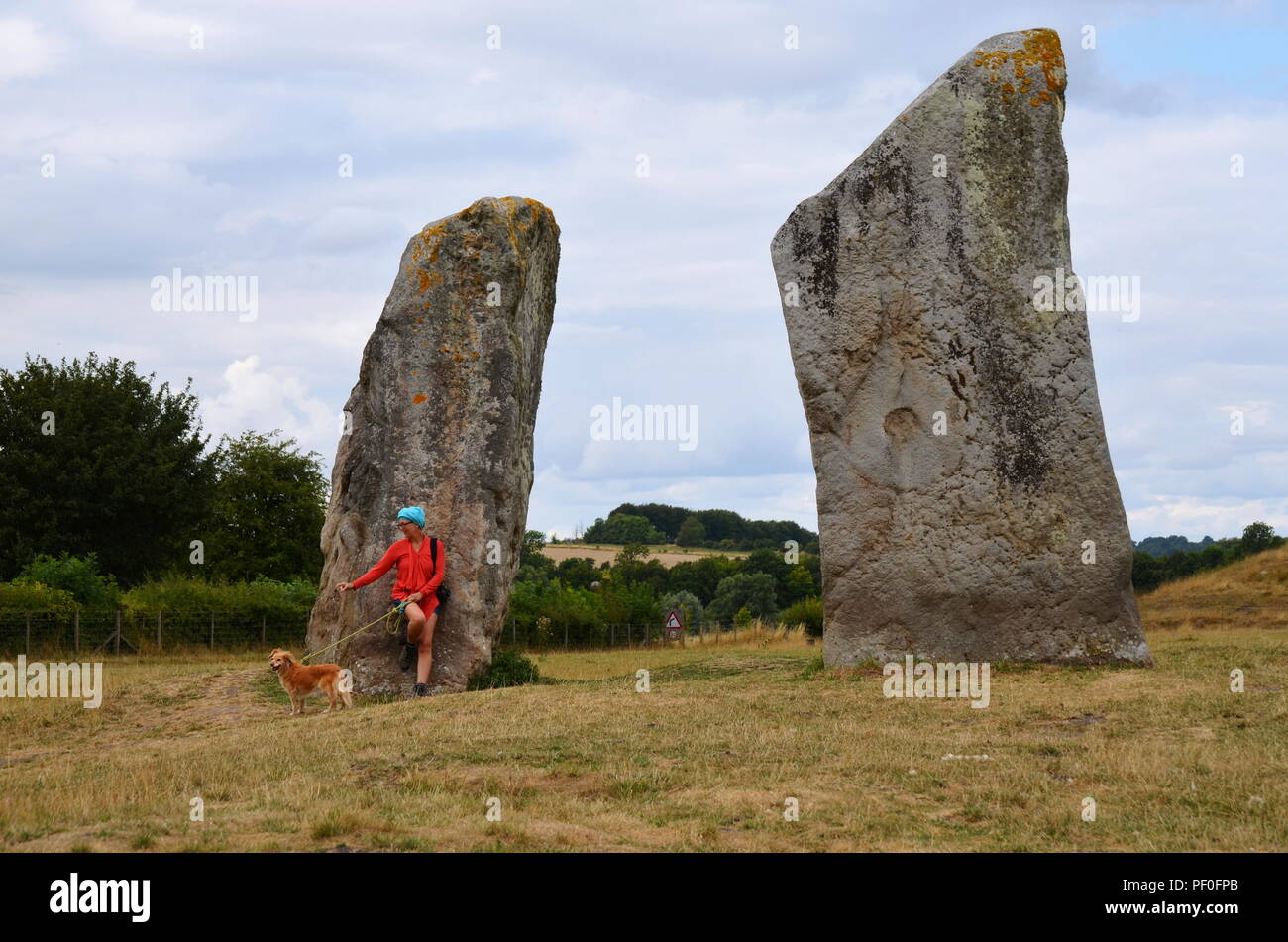 Une femme promener son chien à Avebury, un monument contenant trois cercles de pierres, autour du village d'Avebury dans le Wiltshire, dans le sud-ouest de l'Angleterre. Banque D'Images