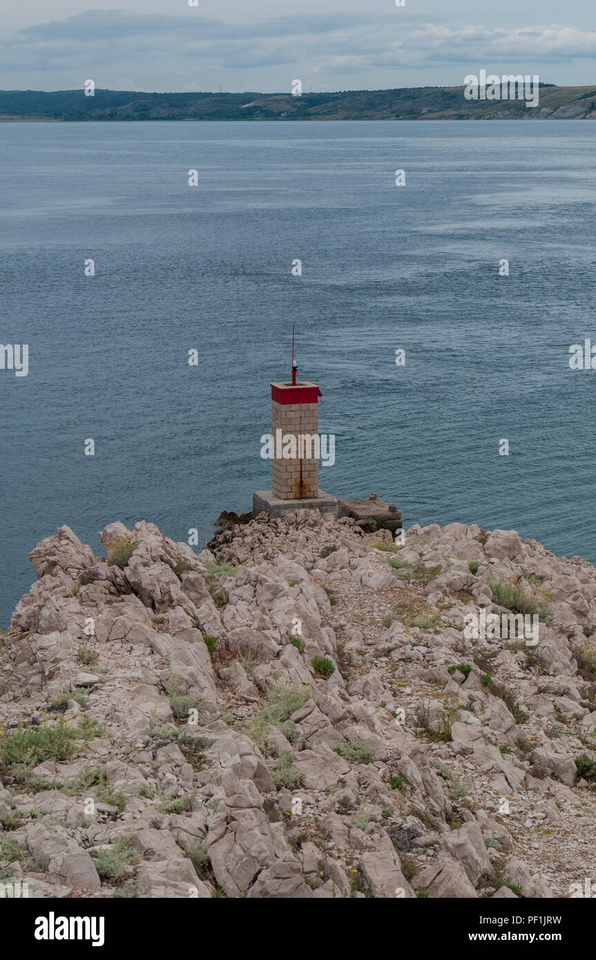 Croatie : temps orageux et le petit phare rouge sur la falaise en face de la plus Paški, 1968 pont qui relie la terre ferme et l'île de Pag Banque D'Images
