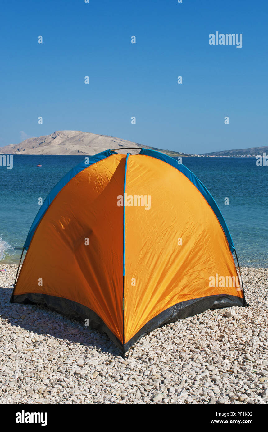 La Croatie, l'Europe : une orange tente à Rucica, la plage de galets située dans une baie aride entourée par un paysage désertique sur la célèbre île de Pag Banque D'Images