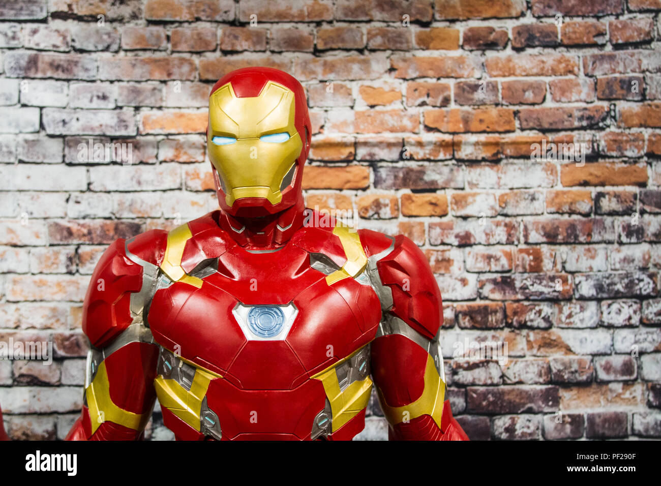 Un mâle cosplayeuse habillée en homme de fer de Marvel comics la franchise film debout devant un mur de briques avec copie espace. Banque D'Images