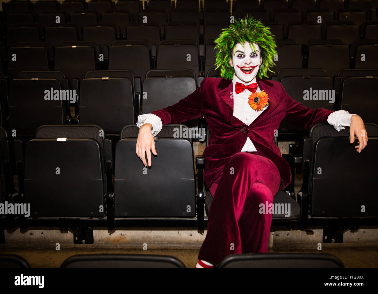 Un homme habillé cosplayeur est un joker de la franchise DC comics Batman et assise seule dans un cinéma abandonné et à la menace Banque D'Images