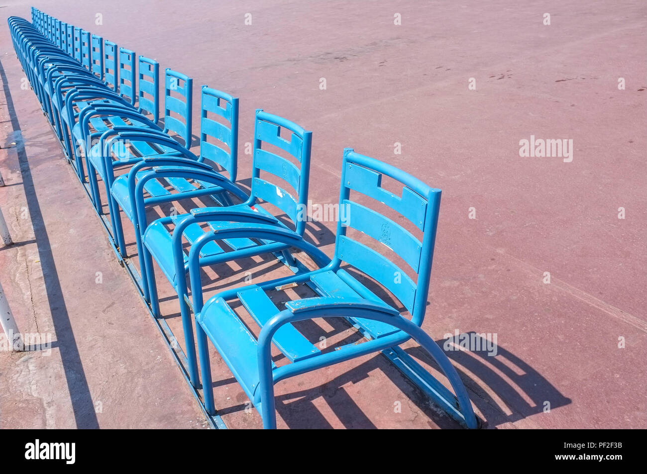Chaises bleu sur la Promenade des Anglais à Nice en France. Banque D'Images