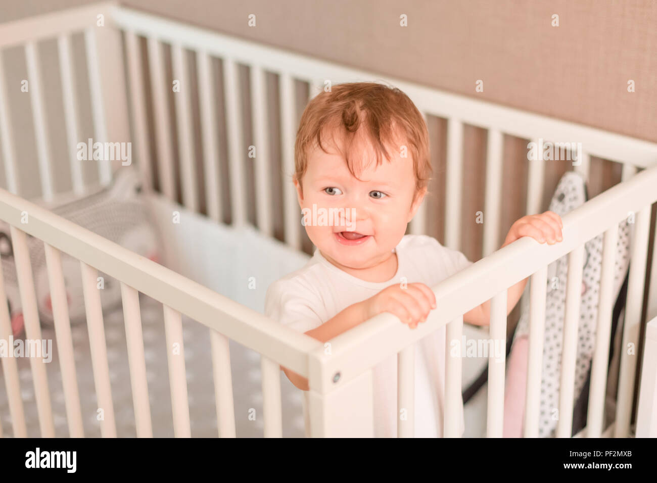 Cute little baby boy looking out de son lit dans sa chambre Banque D'Images