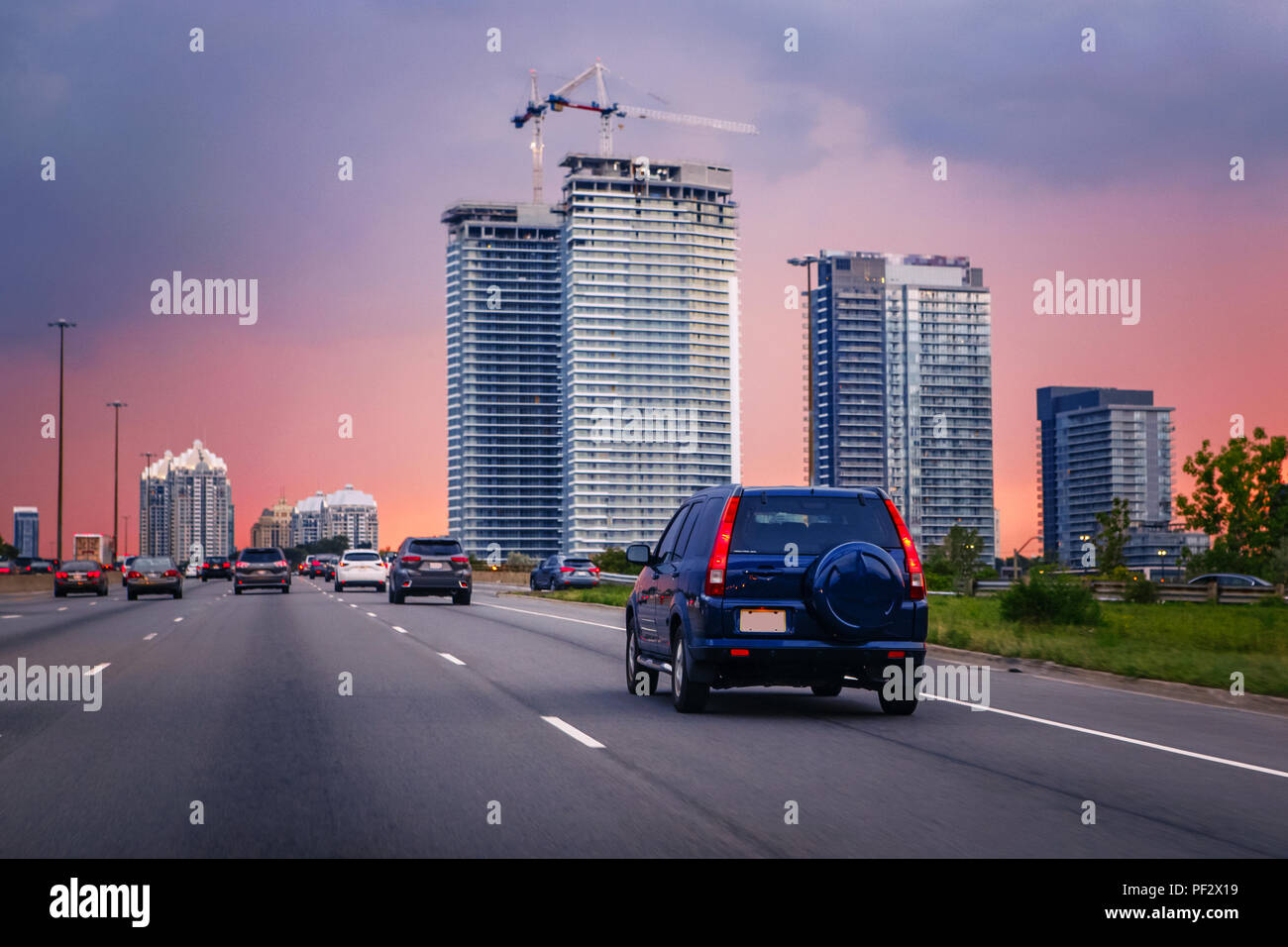 Le trafic de nuit. Voitures sur route autoroute au coucher du soleil en soirée animée typique ville américaine. Belle nuit étonnante vue urbaine avec rouge, jaune et bleu ciel Banque D'Images