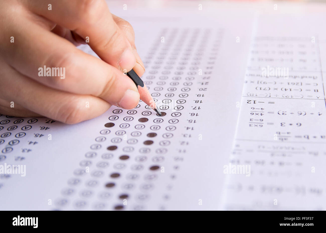 Les élèves hand holding crayon écrivant certains choix sur les feuilles de réponses et mathématiques question feuilles. Les élèves faisant des tests d'examen. examen scolaire Banque D'Images