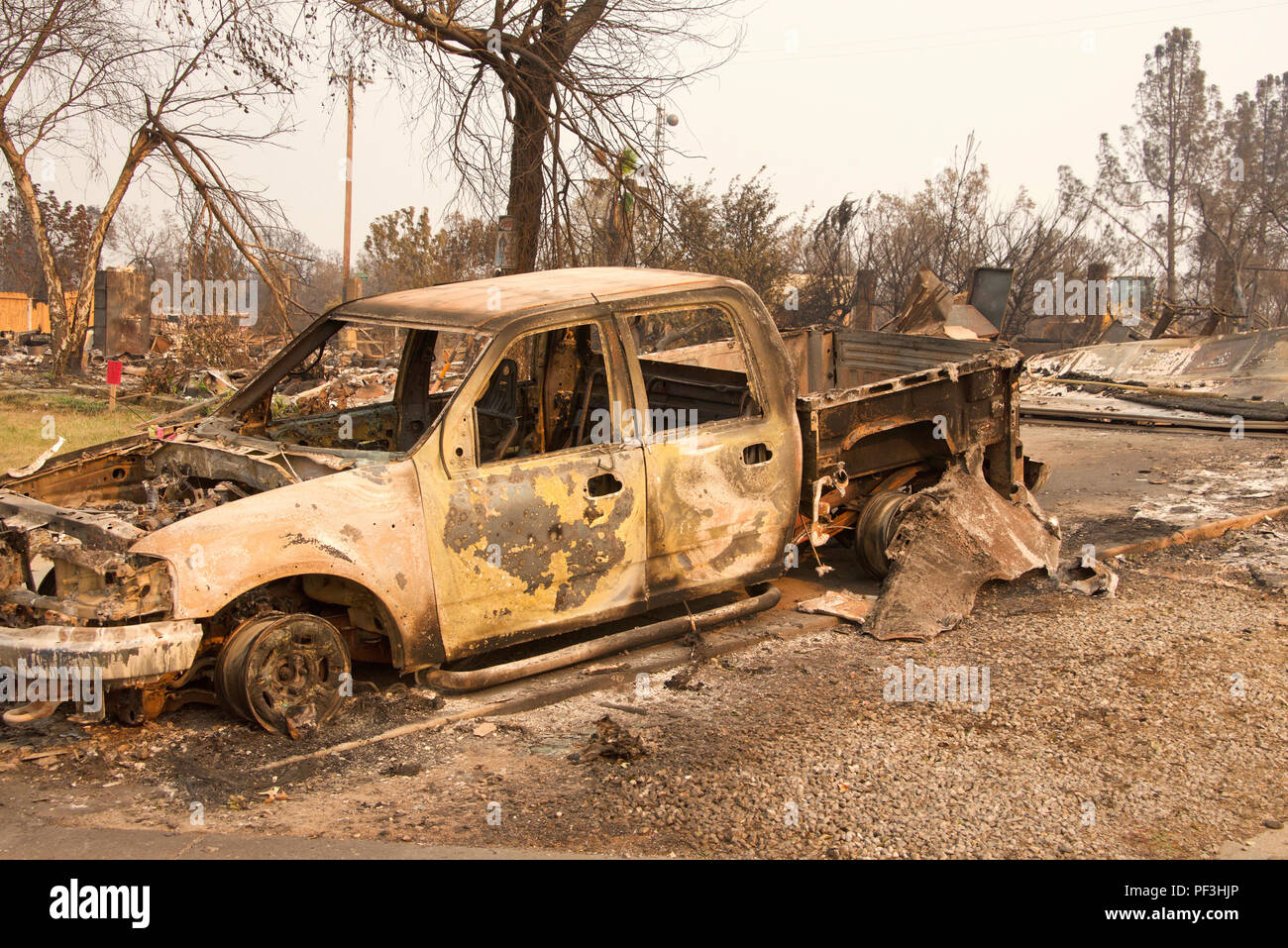 Camion carbonisé en face de la maison a brûlé à la terre dans la récente tempête de feu feu sauvage à Redding en Californie. La fumée et des cendres dans l'air comme le feu co Banque D'Images