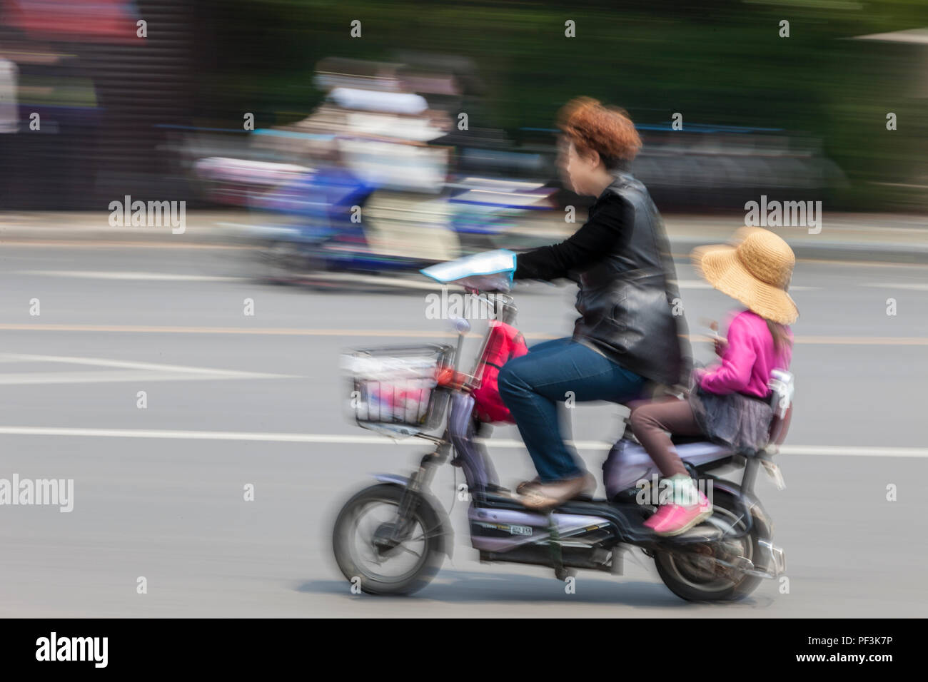 Yangzhou, Jiangsu, Chine. Mère et fille sur une moto électrique. Banque D'Images