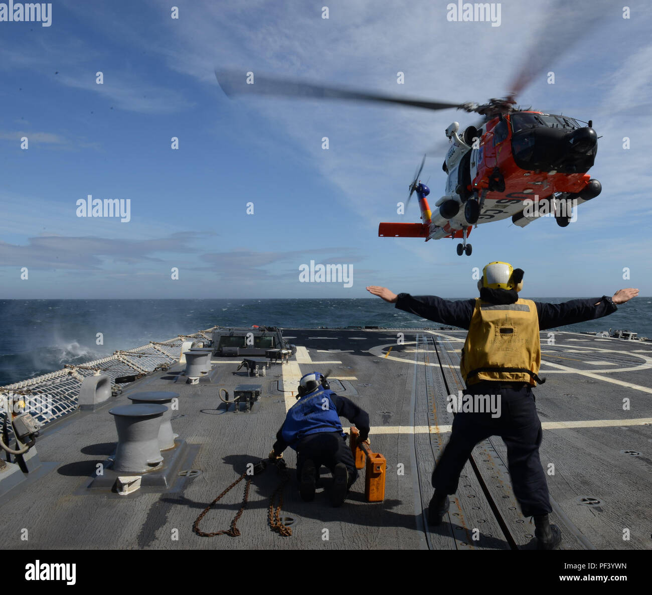 MH-60 Jayhawk est un hélicoptère de transport moyen de la Garde côtière des États-Unis. Les archives photographiques documentent l'équipage effectuant des atterrissages sur le pont de l'USS Momsen (DDG-92) près de Kodiak, en Alaska, en 2018 avec l'aide d'un signaleur d'atterrissage. Banque D'Images