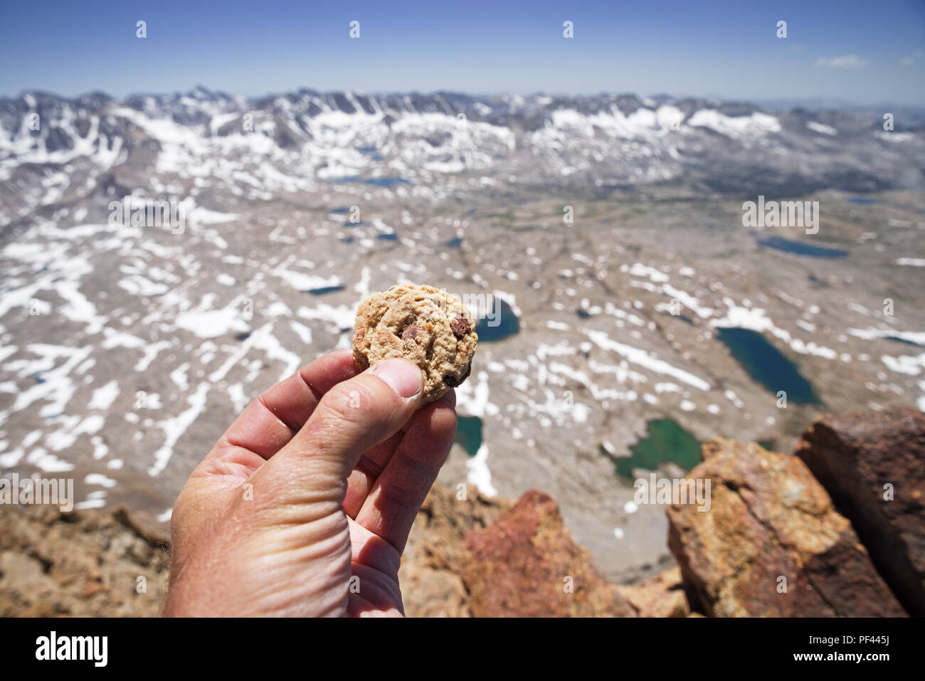 Un mans hand holding a chocolate chip cookie sur le sommet du mont Humphreys dans la Sierra Nevada de Californie Banque D'Images