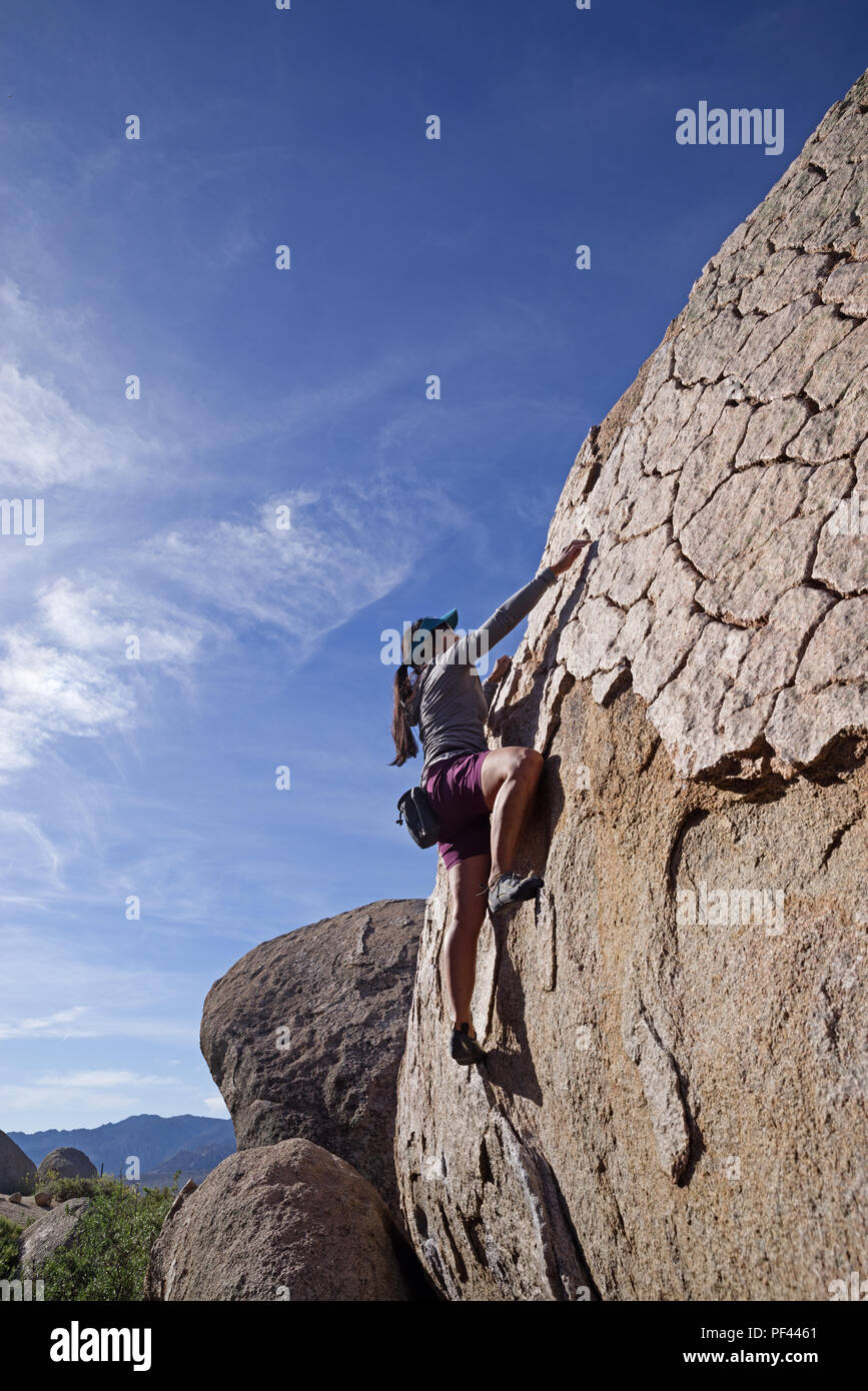 Asian woman rock climber bouldering sur un bloc de granite à la zone d'escalade de babeurre près de Bishop Californie Banque D'Images