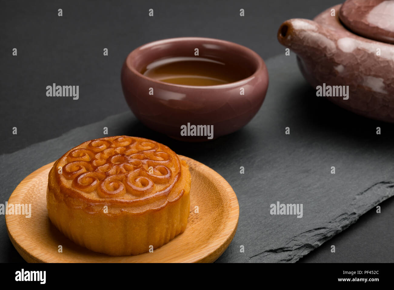 Studio vue côté tige de mooncake traditionnel chinois avec thé et théière sur fond noir Banque D'Images