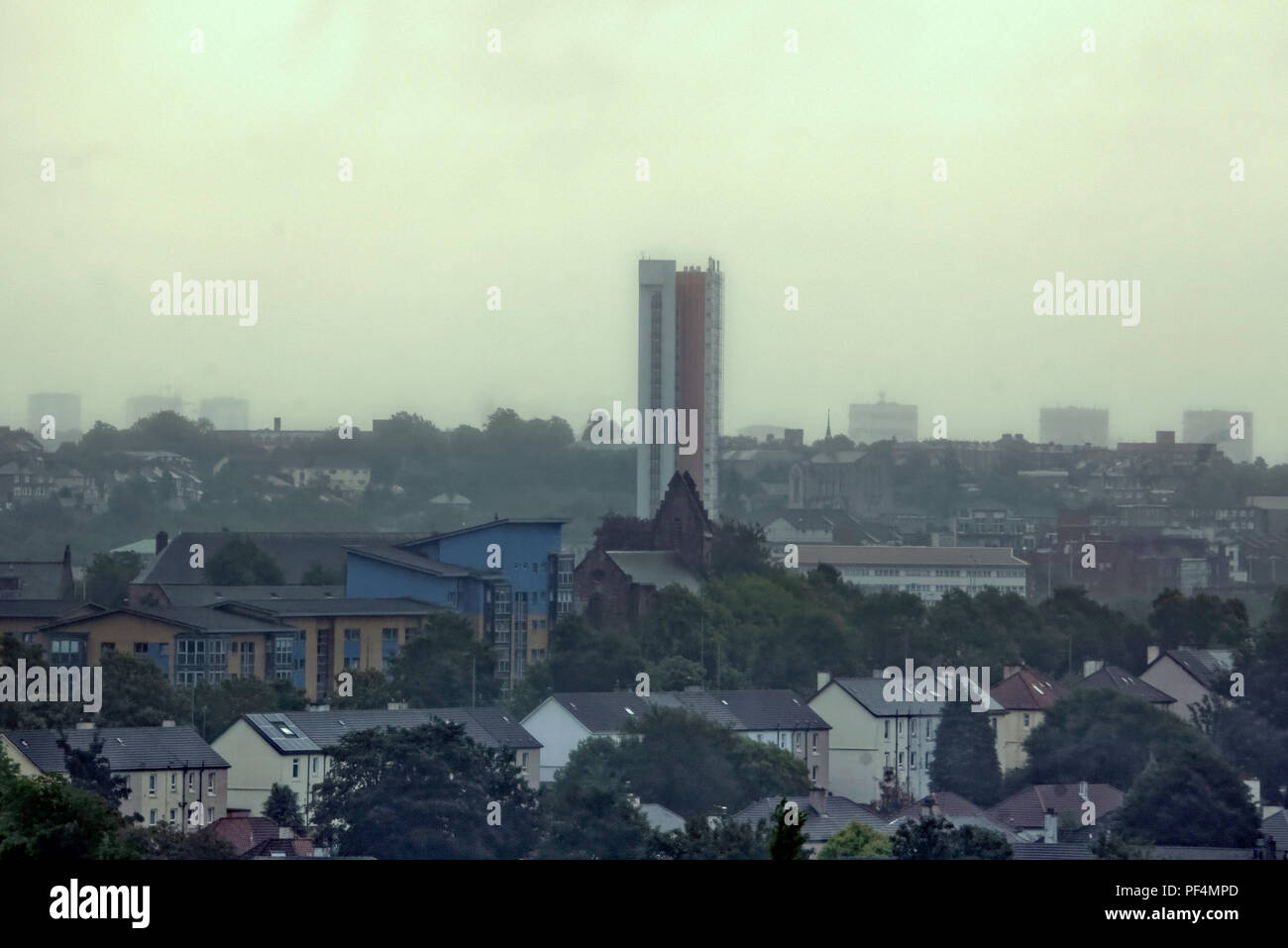 Glasgow, Ecosse, Royaume-Uni. 19 août, 2018. Météo France : Ciel couvert que storm Ernesto est due sur la ville comme une forte pluie et de la brume est prévue par le biais de la journée.Pas d'horizon lointain comme les repères de la ville sont ghosted derrière le réseau express régional de Knightswood semi-détachée. La tour de l'Anniesland, le plus haut bâtiment de l'Ecosse est réduite à un seul tour d'horizon apparaissant pour donner l'oiseau comme les tours et bâtiments de Maryhill fade dans la brume. Gérard Ferry/Alamy news Banque D'Images