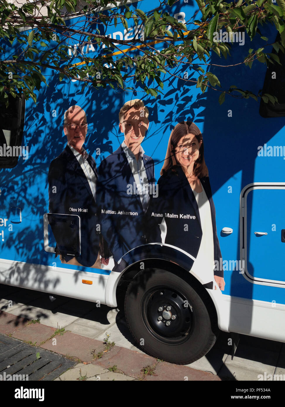 Pré-campagne électorale avec des portraits de la Swedish Parti modéré (M - Modernaterna) candidats, sur un véhicule stationné à côté d'un arbre, casting sa feuille ombres sur les graphiques. Märsta, Sigtuna kommun, Stockholm, Suède. Banque D'Images