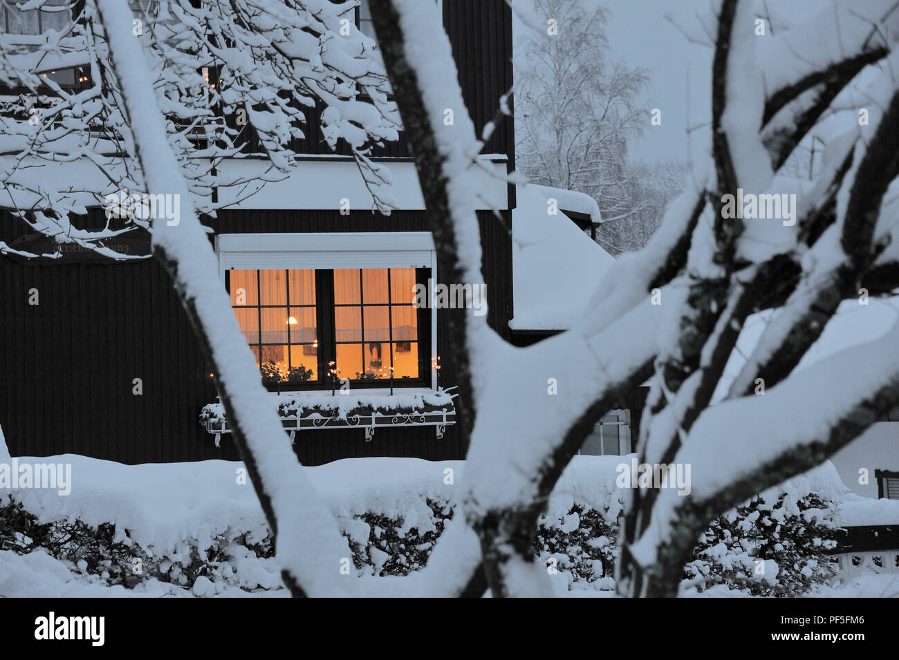Haus beleuchtet mit Schnee bedeckt | maison couverte de neige et d'un fenêtre illuminée Banque D'Images