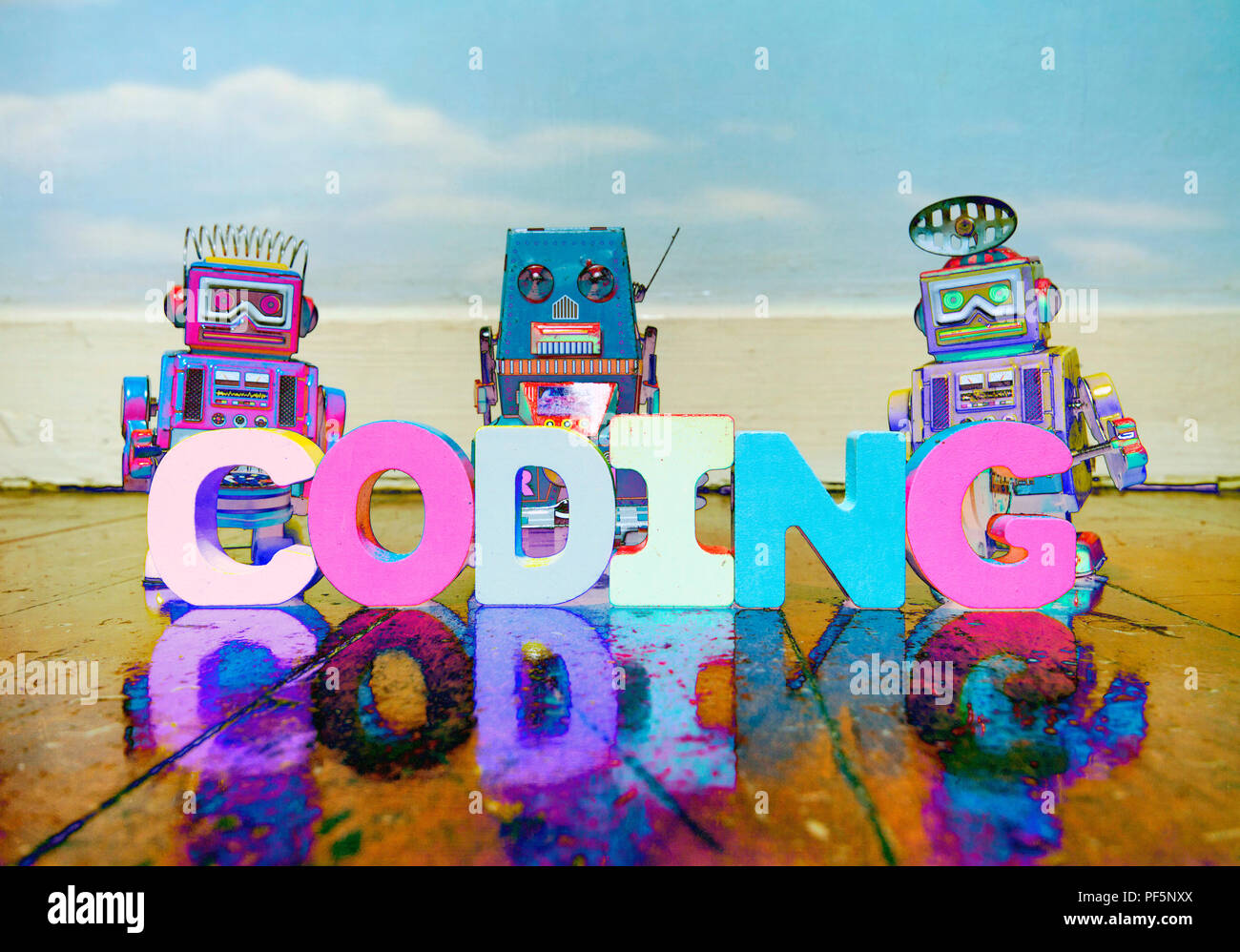 Le mot d'esprit de codage des lettres en bois sur un vieux plancher en bois avec des jouets robot retro Banque D'Images