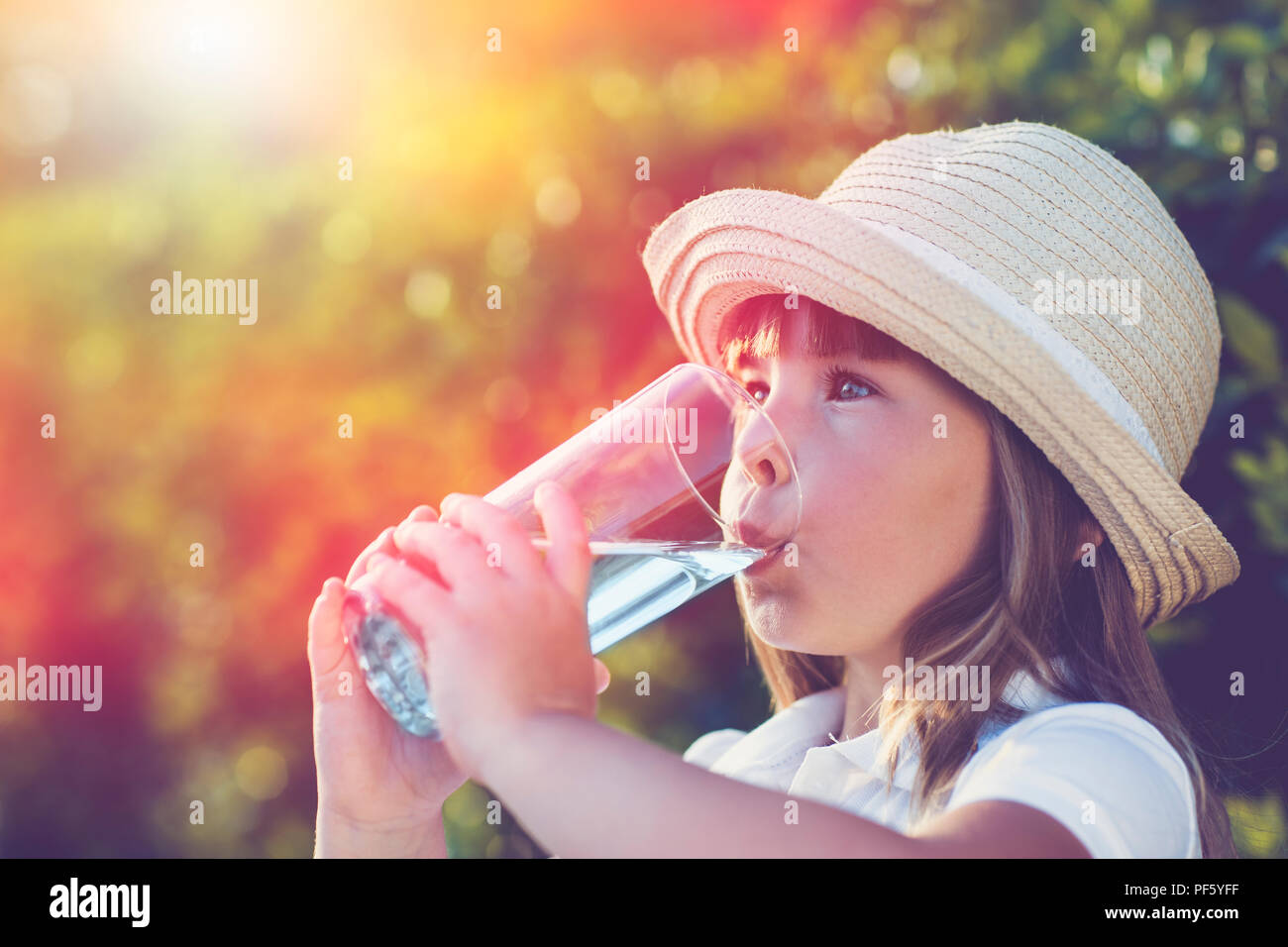 Petite fille de l'eau potable à la côte dans un jardin d'été Banque D'Images