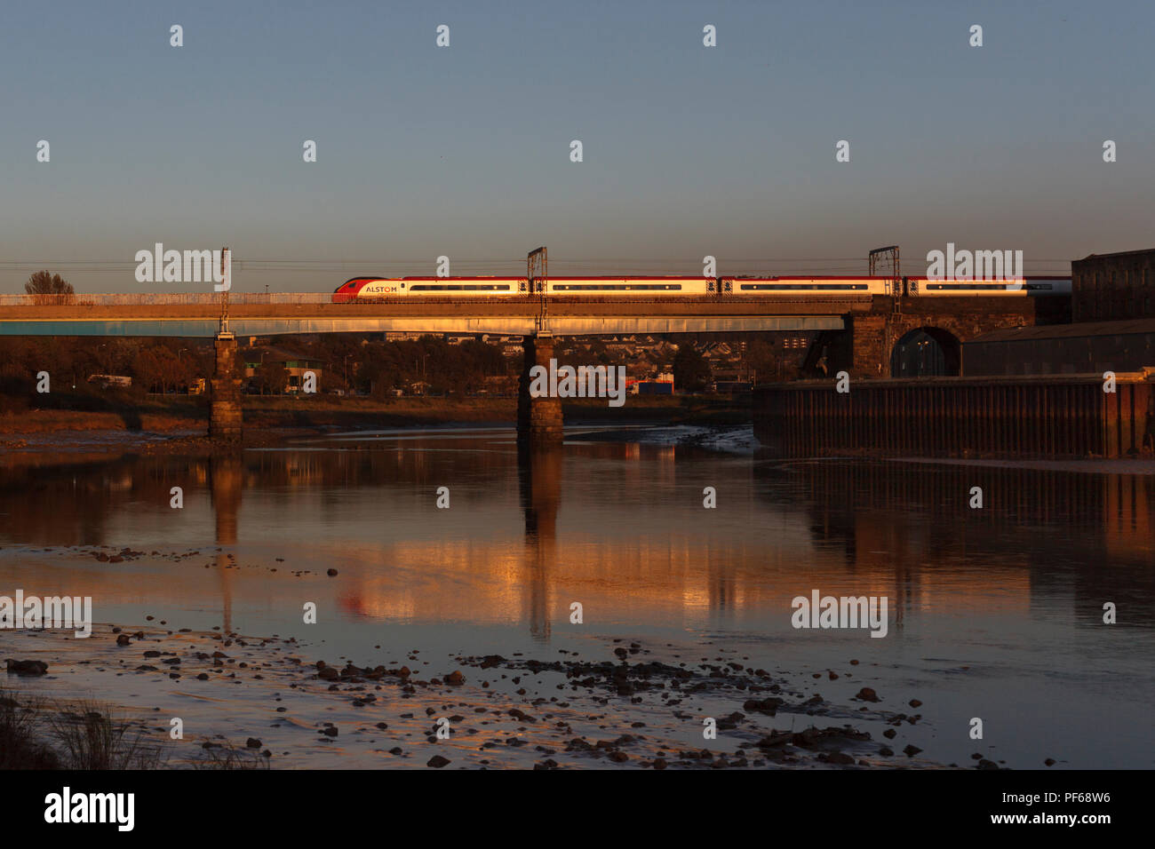 Virgin trains Pendolino 390054 Carlisle crossing Bridge, Lancaster (Rivière Lune) étincelant dans le coucher du soleil et se reflètent dans la rivière Banque D'Images