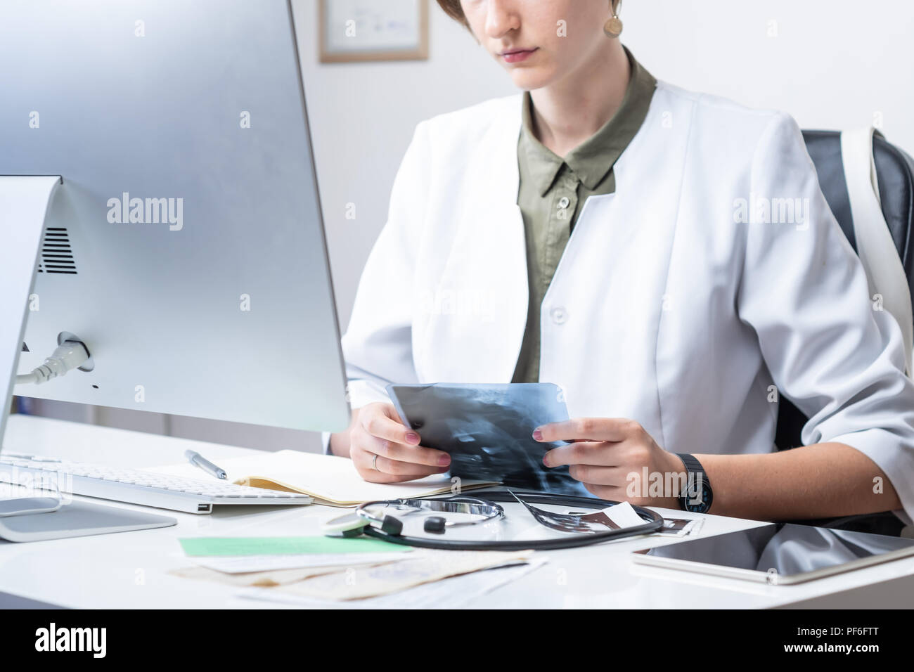 Femme médecin à médecin moderne bureau. Woman examining x-ray sur le lieu de travail devant un ordinateur de bureau Banque D'Images