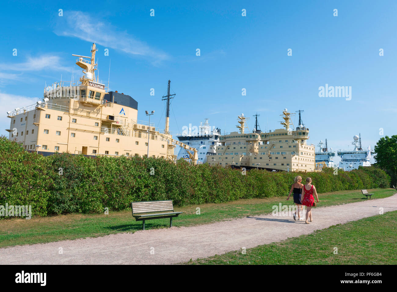 Parc d'Helsinki, vue de deux jeunes femmes finlandaises walking in City Park sur l'île de Katajanokka, avec un groupe d'énormes amarrés à proximité d'Helsinki, brise-glace. Banque D'Images