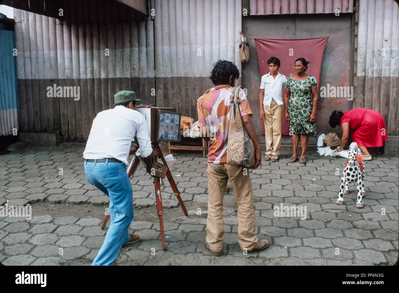 Managua, Nicaragua, juillet 1986 ; photographe Astreet fait un portrait d'une mère et son fils, à l'aide de l'appareil photo à développer l'impression finale. Banque D'Images